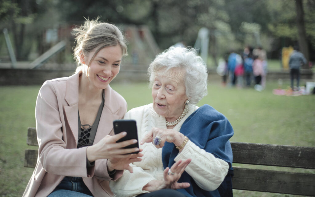 Donna mostra il suo telefono a una donna anziana