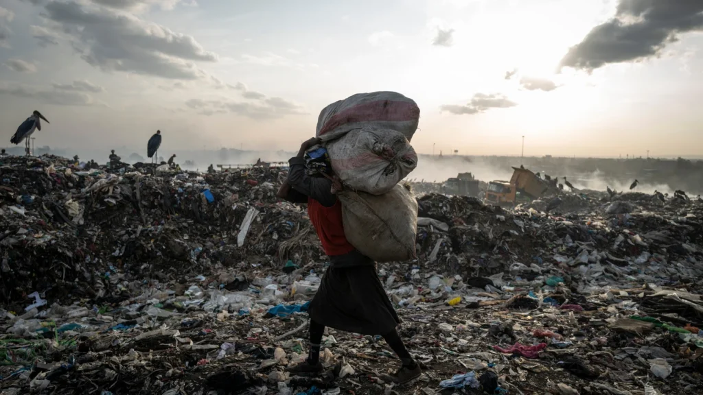 Foto di una donna che cerca vestiti in una discarica in Africa.